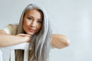 Ältere Frau mit grauen Haaren auf Stuhl