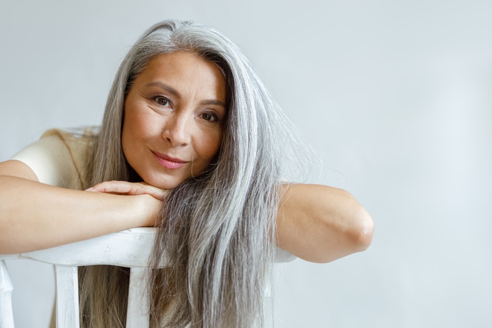 Ältere Frau mit grauen Haaren auf Stuhl