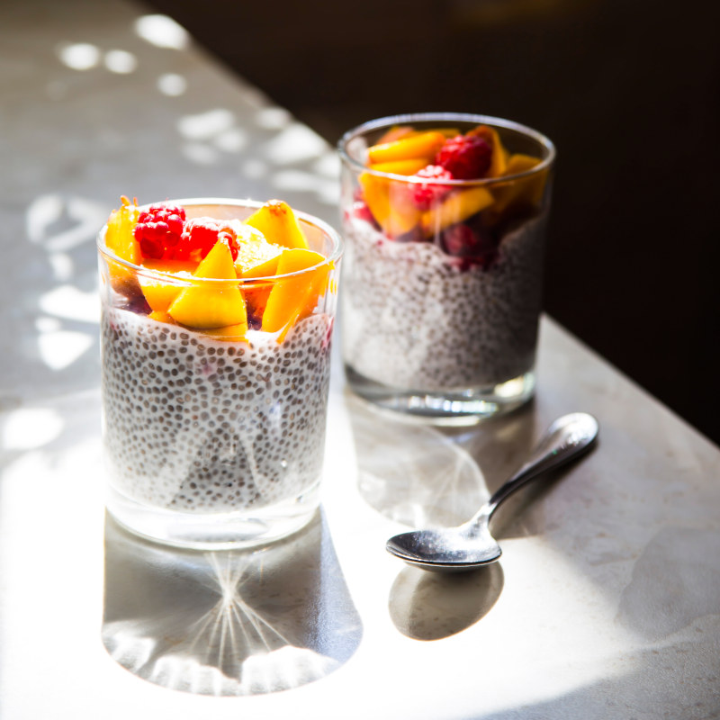 Chia pudding auf Kokosmilchmit Himbeeren und Pfirsich im Glas