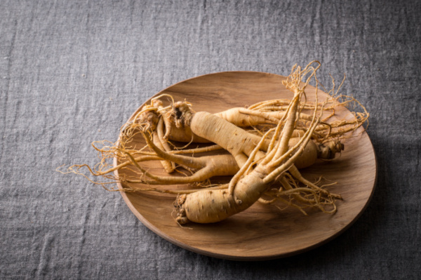 Ginseng in Holzschale auf grauer Tischdecke