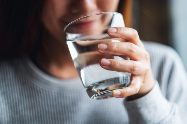 Frau trinkt aus einem Glas Wasser