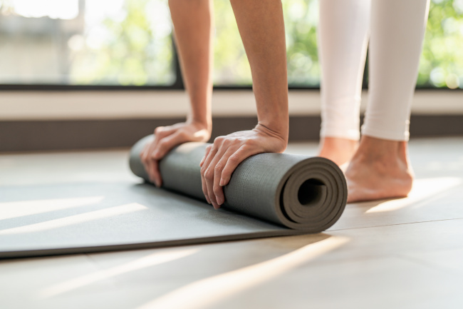 Frau faltet eine Yogamatte