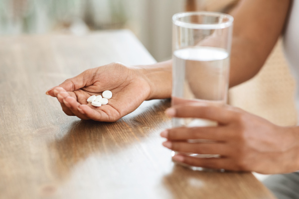 Frau mit einer Hand voll Magnesiumtabletten und einem Glas Wasser